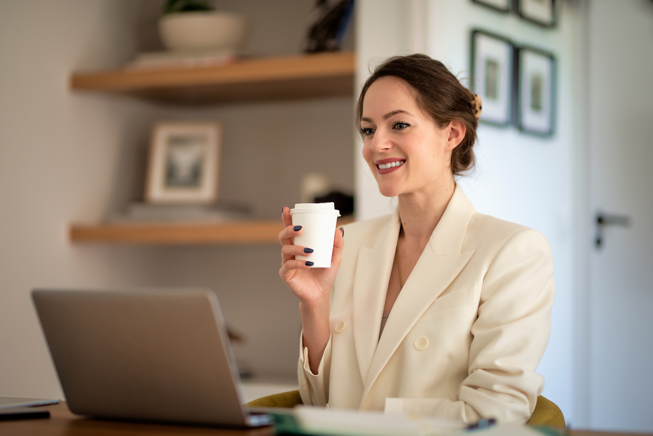 Smiling youg woman sitting at home and using laptop for work